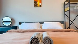 A neatly made bed with a beige bedspread and two rolled towels placed on the bed. - JQ Central 4 person unit facing mountain view and partially seaview AT kk CITY CENTER (Kota Kinabalu)