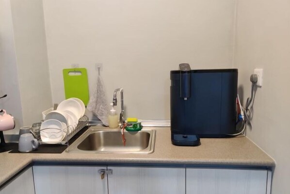 A kitchen with a sink, a dish rack, a coffee maker, and a water dispenser. - JQ Central 4 person unit facing mountain view and partially seaview AT kk CITY CENTER (Kota Kinabalu)