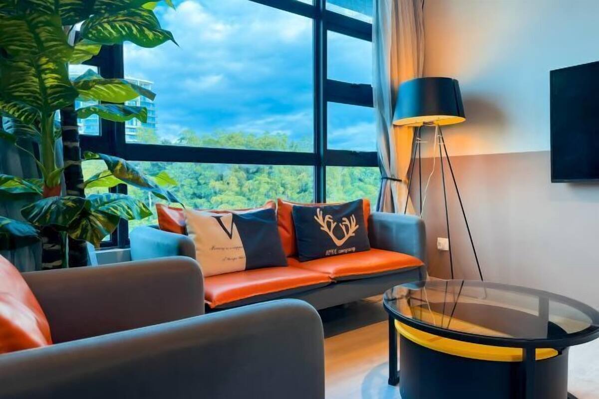 Una sala de estar moderna con un sofá, una mesa de centro de vidrio, una lámpara de pie y ventanas amplias con vistas a zonas verdes.