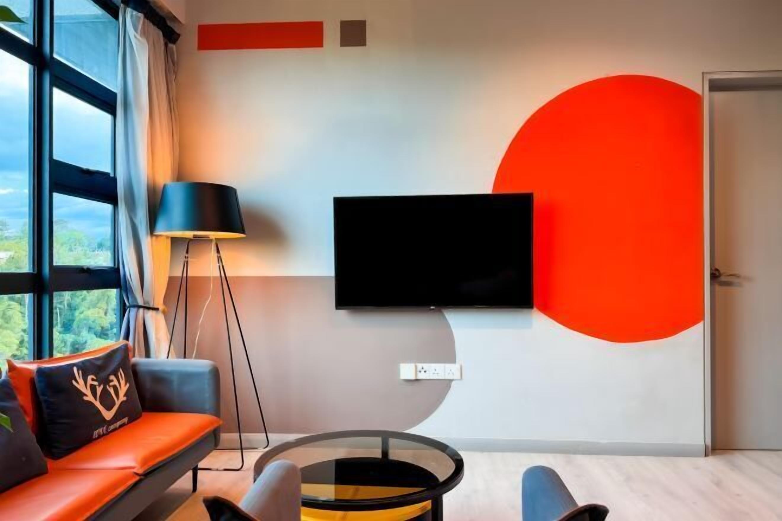 A modern living room with a sofa, a coffee table, a floor lamp, and a TV mounted on the wall.