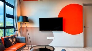 A modern living room with a sofa, a coffee table, a floor lamp, and a TV mounted on the wall. - JQ Central 4 person unit facing mountain view and partially seaview AT kk CITY CENTER (Kota Kinabalu)