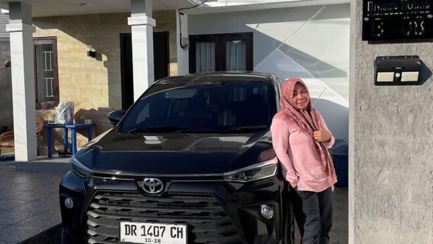 A black Toyota SUV parked in front of a building with a white facade and a blue door. - Breeze House (West Lombok Regency)