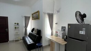 A compact living space with a kitchenette, a sofa, a small table, and a refrigerator. - Breeze House (West Lombok Regency)