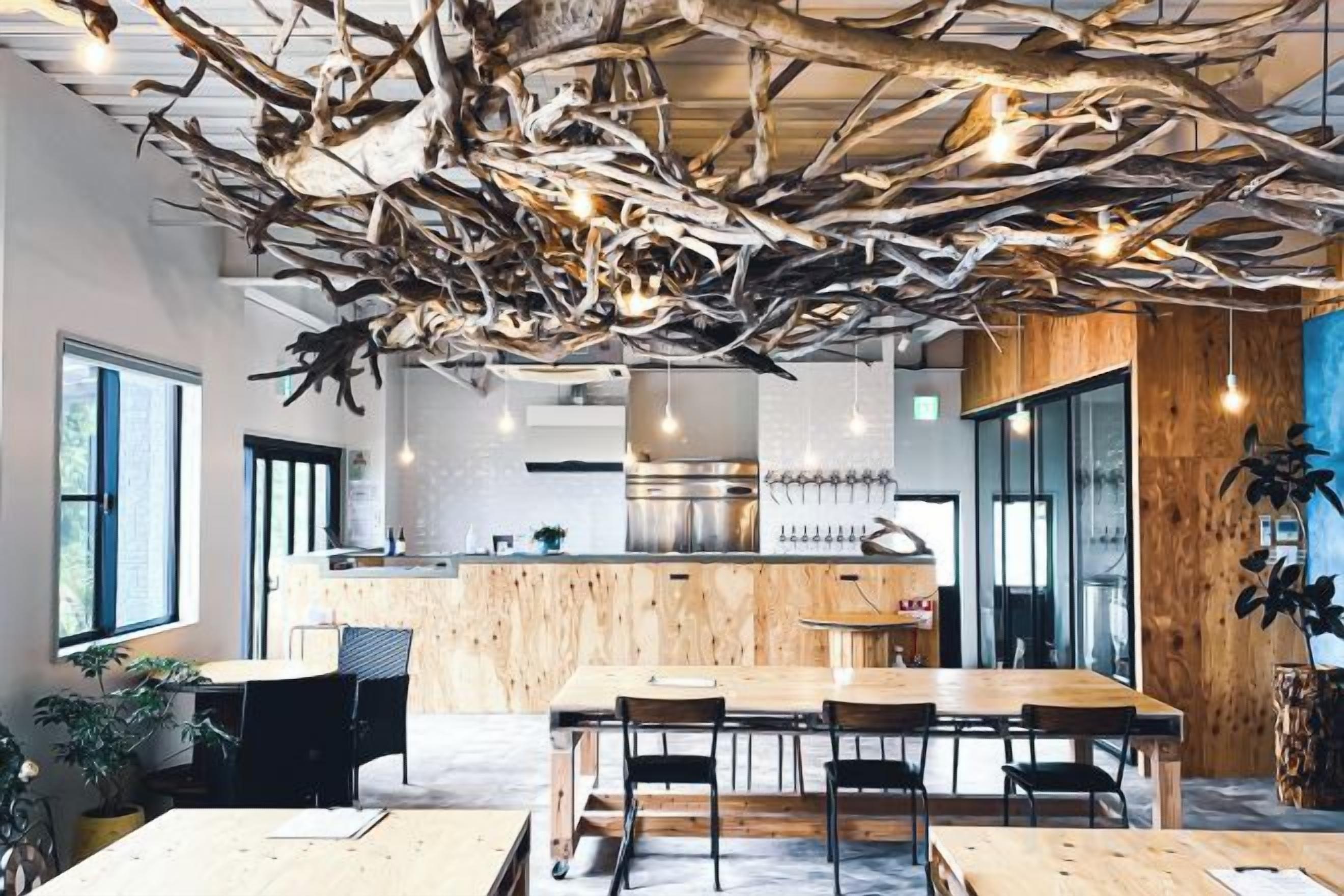 Un comedor moderno con una mesa y sillas de madera, una cocina al fondo y un diseño de techo original.