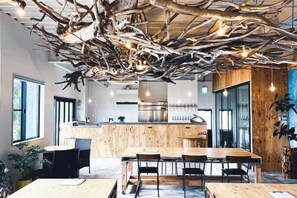 Un espace de repas moderne avec une table et des chaises en bois, une cuisine en arrière-plan et un design de plafond original.