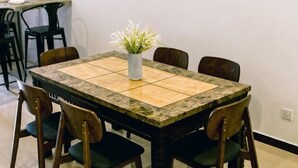 A dining table with a vase of flowers, surrounded by chairs. - Karking 15@Pinjistation (8pax/4br) (Ipoh)