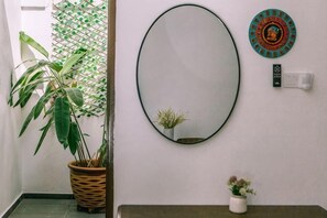 Un corridoio con una pianta in vaso, uno specchio e un piatto decorativo appeso al muro.