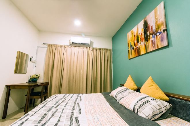 A bedroom with a bed, a desk, a chair, a window with curtains, and a wall-mounted air conditioner.
