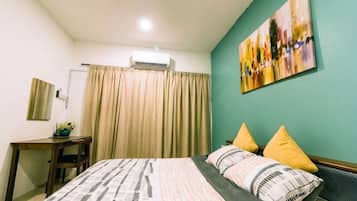 A bedroom with a bed, a desk, a chair, a window with curtains, and a wall-mounted air conditioner.