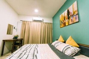 Une chambre à coucher comprenant un lit, un bureau, une chaise, une fenêtre avec des rideaux et un climatiseur fixé au mur.