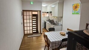 A compact kitchen with a dining area, a sliding door, and a painting on the wall. - XUYUAN (Osaka)