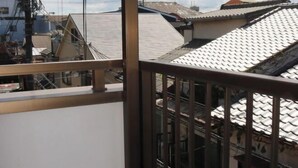 A residential area with traditional Japanese-style buildings, a wooden balcony, and a view of neighboring houses. - XUYUAN (Osaka)