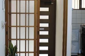 Una habitación con puerta corredera, una planta en maceta y pared de azulejos.