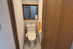 A small bathroom with a toilet, a window, and a towel rack. - XUYUAN (Osaka)