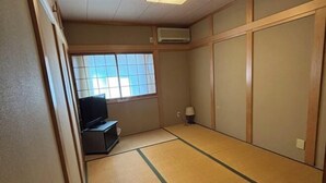 A traditional Japanese room with tatami flooring, a television, and sliding doors. - XUYUAN (Osaka)