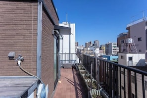 A narrow balcony with a metal railing, a hose, and a water tap on the left side.