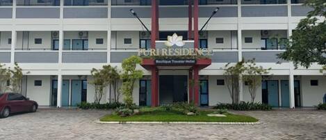 A multi-story building with a central entrance, a logo, and a sign indicating it is a boutique traveler hotel.