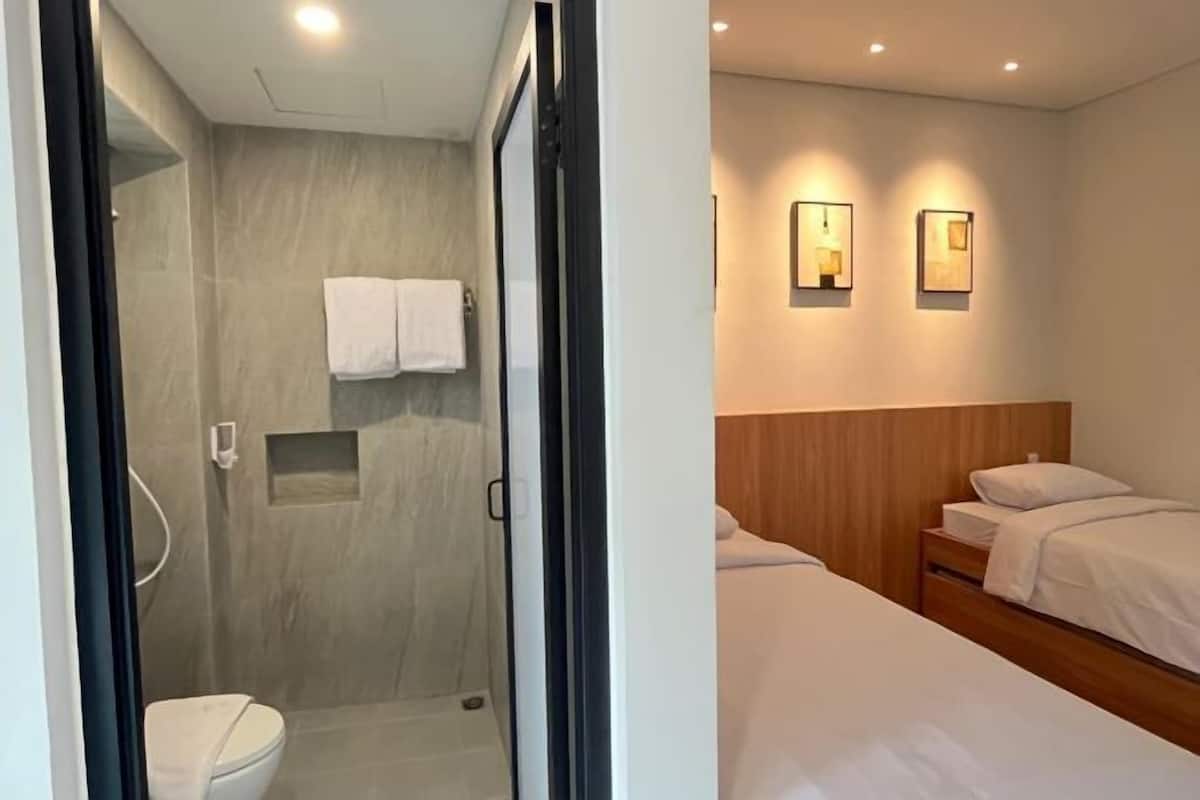 A modern bathroom with a glass-enclosed shower, a toilet, and a towel hanging on the wall.