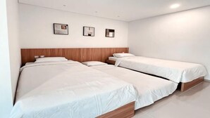 A hotel room with two beds, a wooden headboard, and three framed pictures on the wall. - Puri Residence Hotel (Sananwetan)