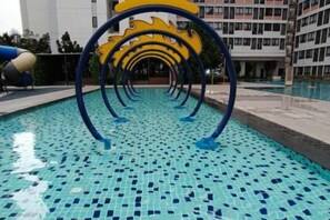 A swimming pool with a tiled floor and a series of blue and yellow circular structures. - The Transit Loft - Warisan StayHub (Dengkil)