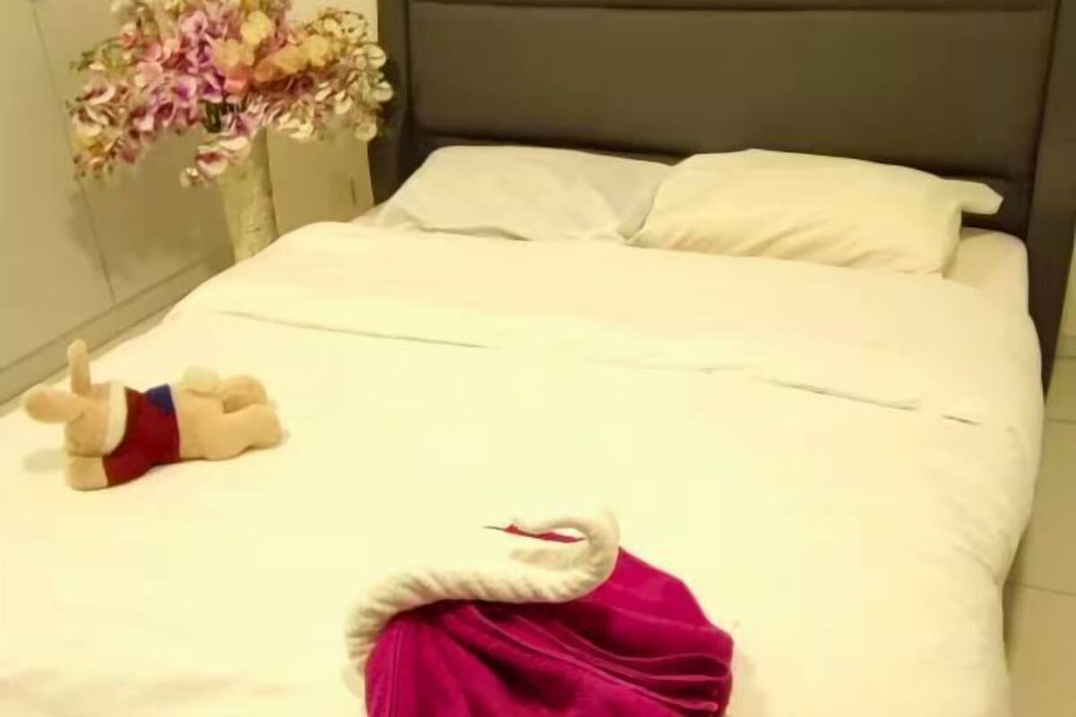 A neatly made bed with white linens, a plush toy, and a decorative swan.