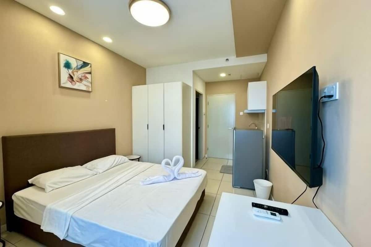 A hotel room with a bed, a TV, a desk, and a wardrobe.