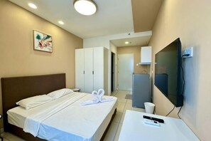 A hotel room with a bed, a TV, a desk, and a wardrobe. - The Transit Loft - Warisan StayHub (Dengkil)