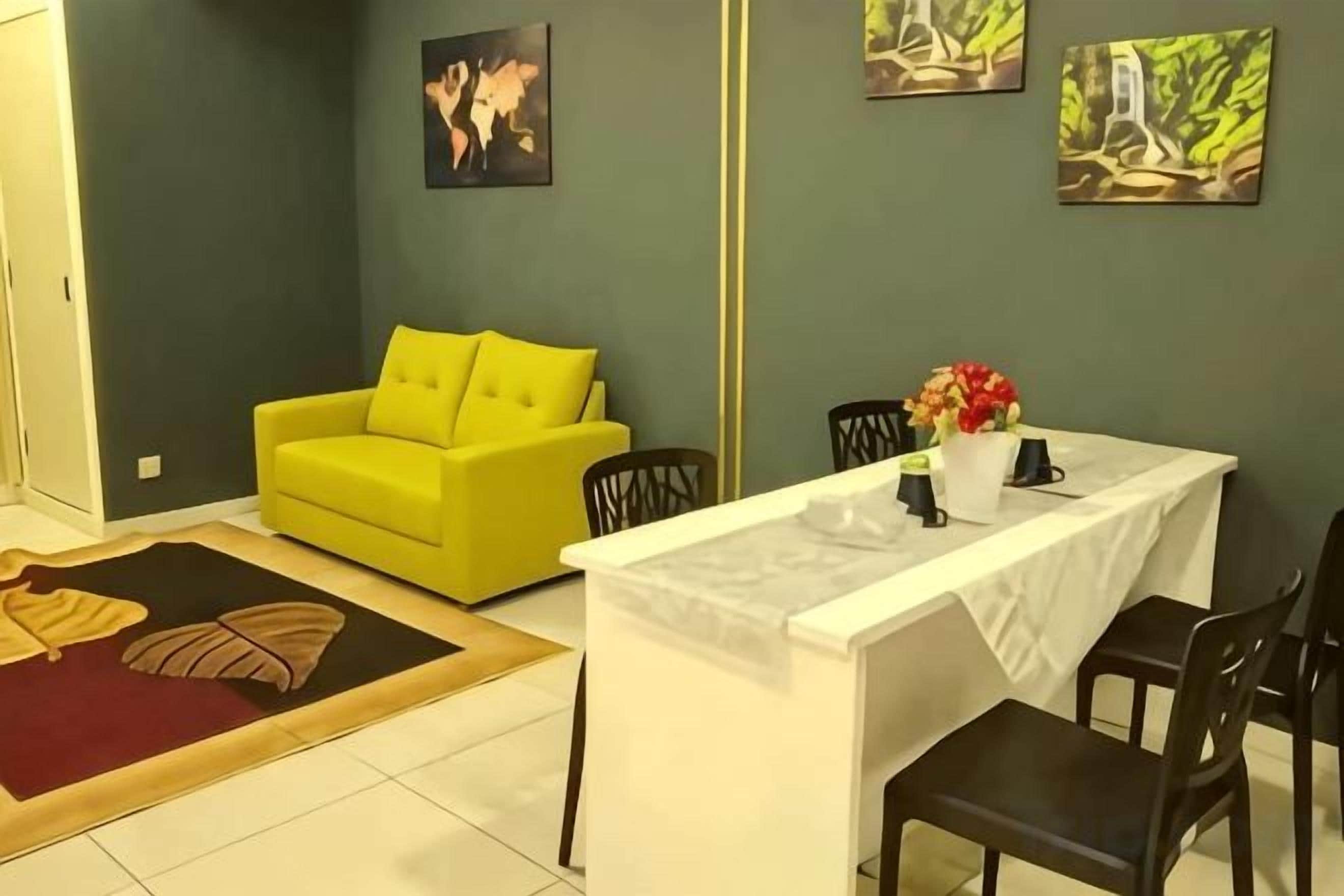 A room with a yellow sofa, a dining table with chairs, and artwork on the walls.