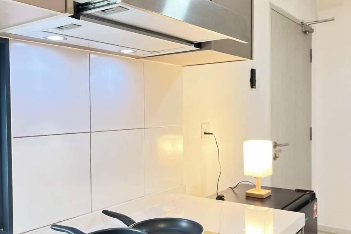 Una cocina moderna con azulejos blancos, una campana extractora de acero inoxidable y una encimera negra.