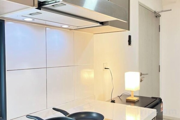 A modern kitchen with a stove, a sink, and a countertop. - The Transit Loft - Warisan StayHub (Dengkil)