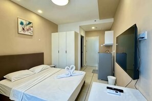 Una habitación de hotel con una cama, un televisor y un armario.