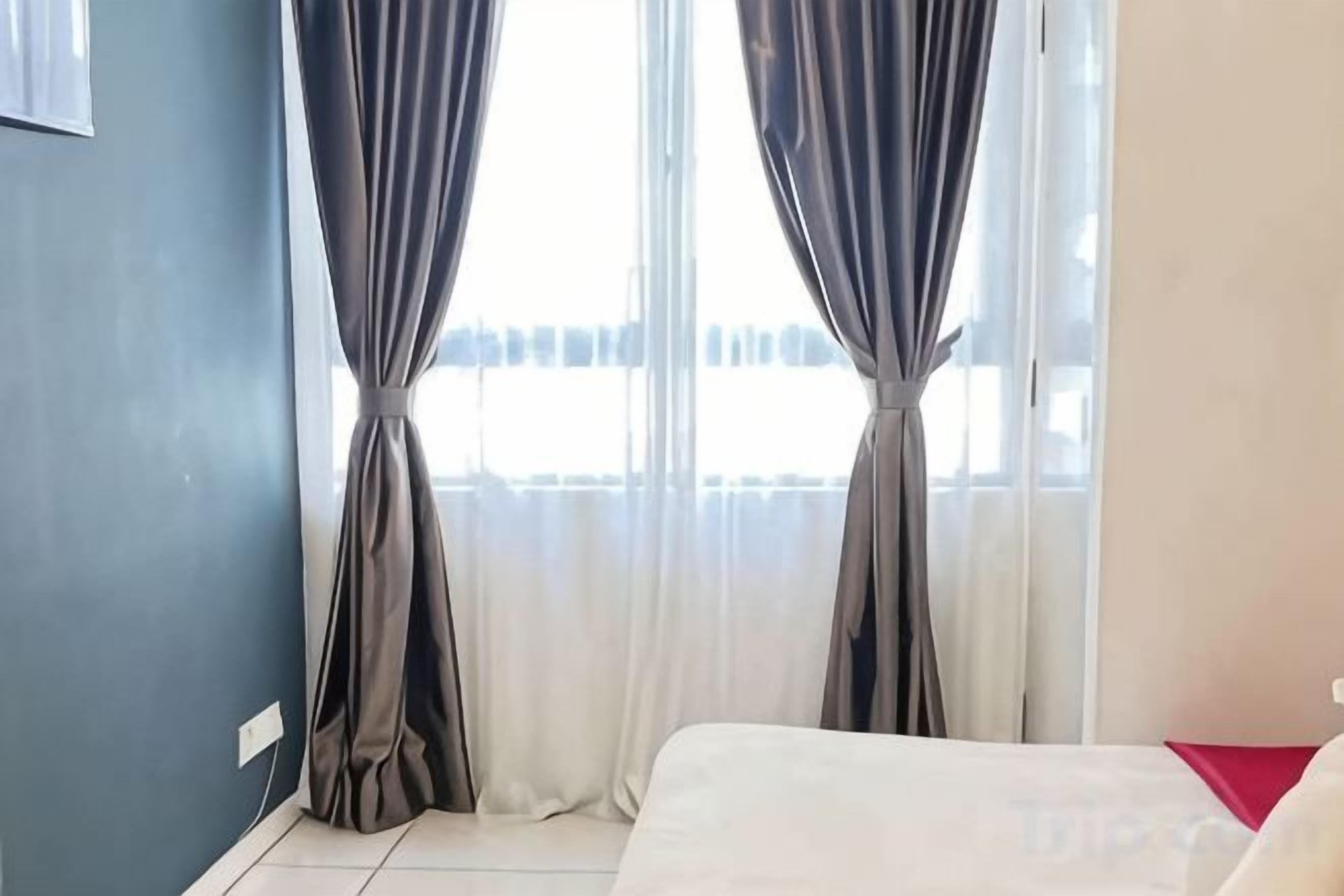 A room with a bed, a window with curtains, and a view of the outside.