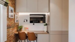 A compact kitchen with a built-in microwave, two chairs, and a small table. - Kensington Cosy Studio (London)