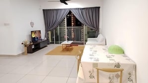 A living room with a dining table, chairs, a TV, and a balcony with curtains. - Aliff Avenue 1103 By Natol (Tebrau)