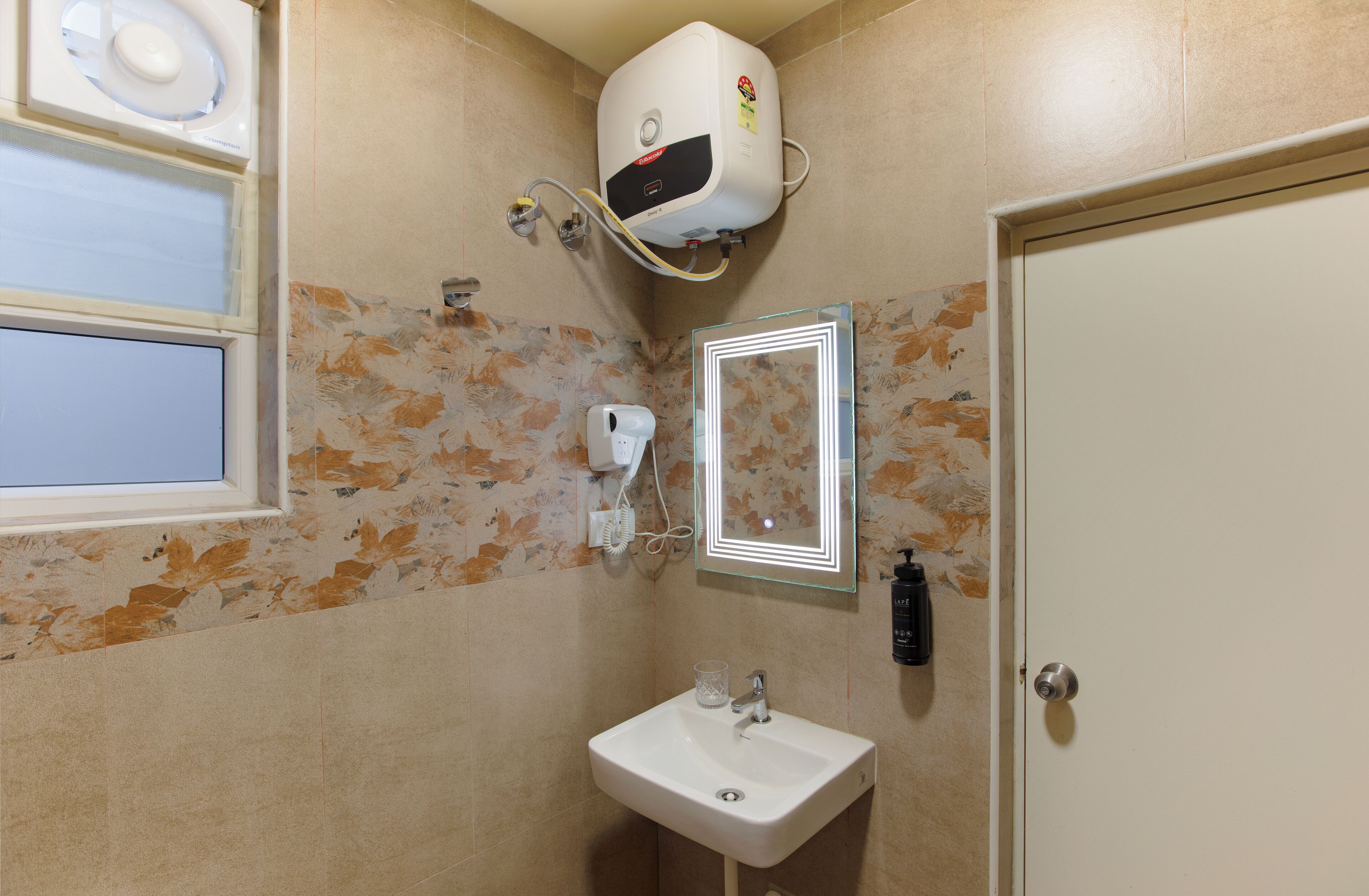Une salle de bain avec un lavabo blanc, un miroir, un sèche-cheveux et un radiateur fixé au mur.