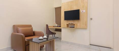 A modern living room with a sofa, a coffee table, and a flat-screen TV mounted on the wall.