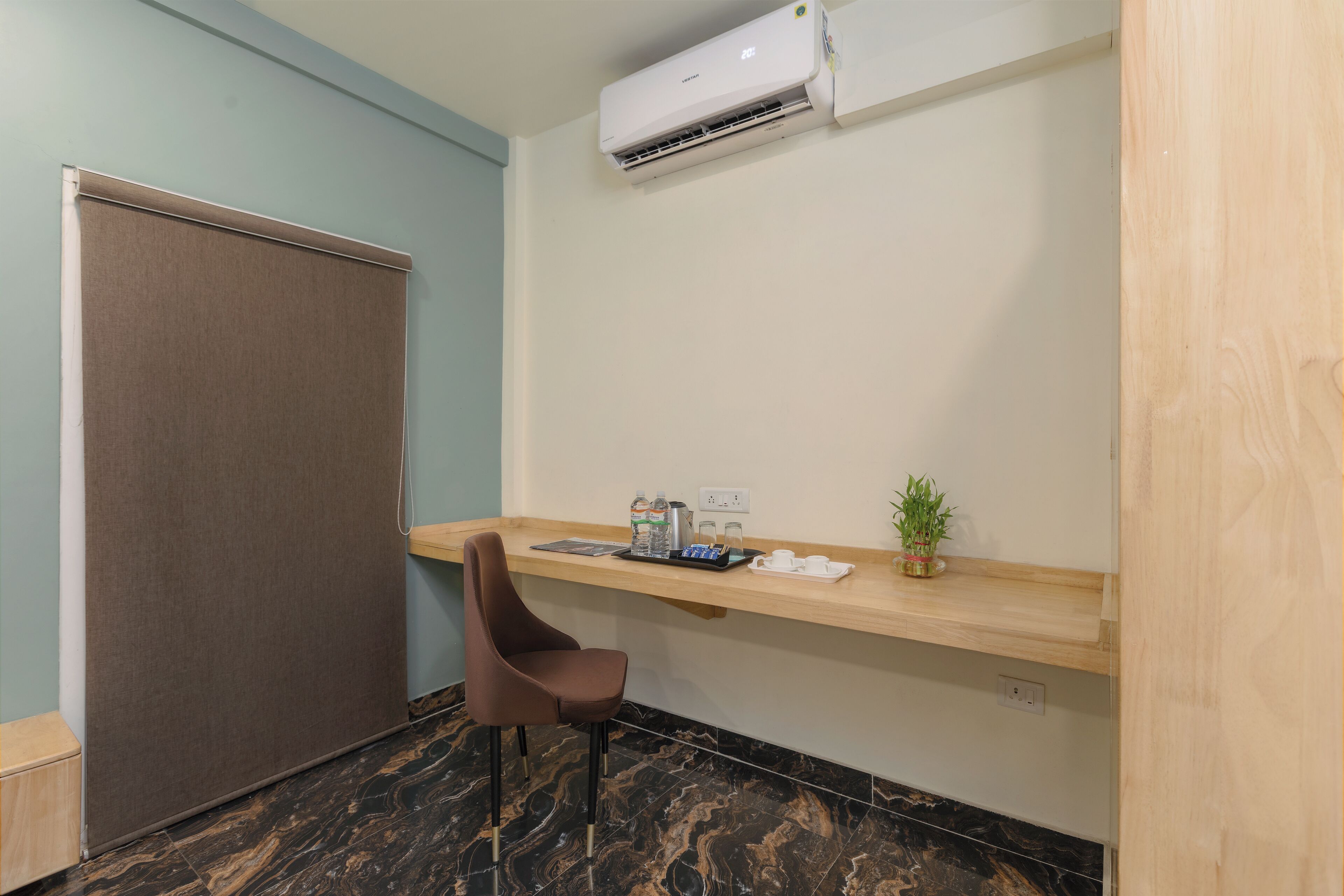 A small room with a desk, chair, and an air conditioning unit.