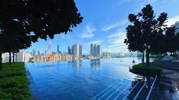 A rooftop infinity pool with a city skyline view, surrounded by greenery and modern architecture. - M Vertica KL City 4 Bedroom Fully Air-Con Suite (Kuala Lumpur)
