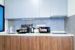 A kitchen with a white countertop, wooden cabinet, and various kitchen utensils. - M Vertica KL City 4 Bedroom Fully Air-Con Suite (Kuala Lumpur)