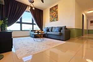 A modern living room with a sofa, coffee table, and a large window with curtains.