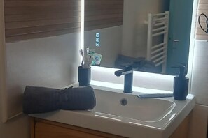 A bathroom with a white sink, blue faucets, and a towel on the counter. - New Studio/Near Airport CDG/Direct Paris center/Disneyland/Villepinte EXPO (Tremblay En France)