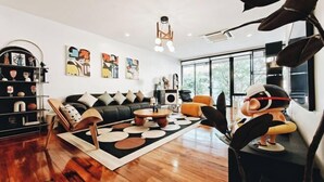 A modern living room with a black sofa, a round coffee table, and a large window. - 4Br Modern Art Villa with Free Wi-Fi Netflix Vinyl (Bangkok)