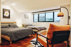 Un dormitorio con dos camas, un escritorio y una silla. Una ventana ofrece vistas al exterior.