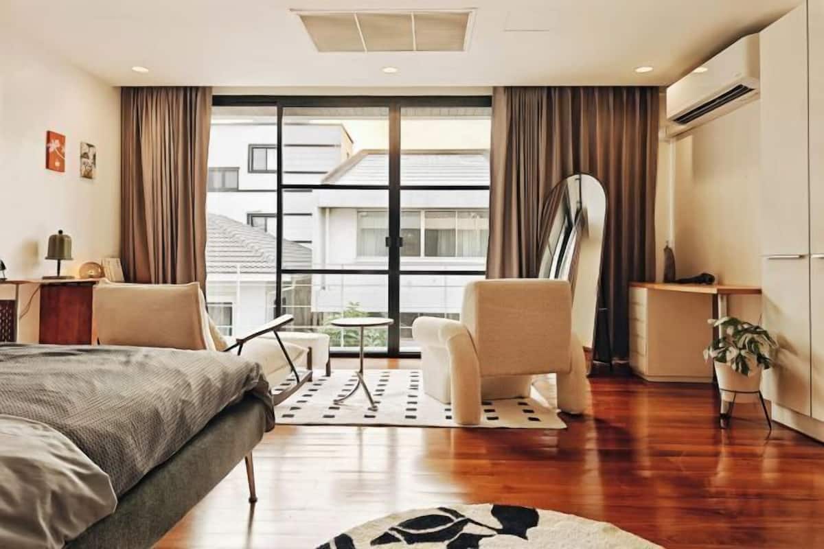 Une chambre d’hôtel moderne équipée d’un lit, d’un bureau, d’une chaise et d’une grande fenêtre avec des rideaux.