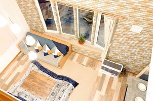A room with a sofa, a small table, a potted plant, and a window with curtains.