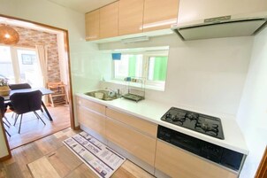 A compact kitchen with a gas stove, a sink, and wooden cabinets.