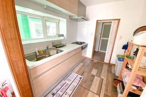 A compact kitchen with a sink, stove, and a window. - Pokke (Shiraoi)