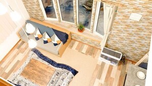 A room with a sofa, a small table, a potted plant, and a window with curtains. - Pokke (Shiraoi)