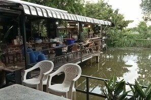 A riverside restaurant with outdoor seating, a covered area, and a view of the water.
