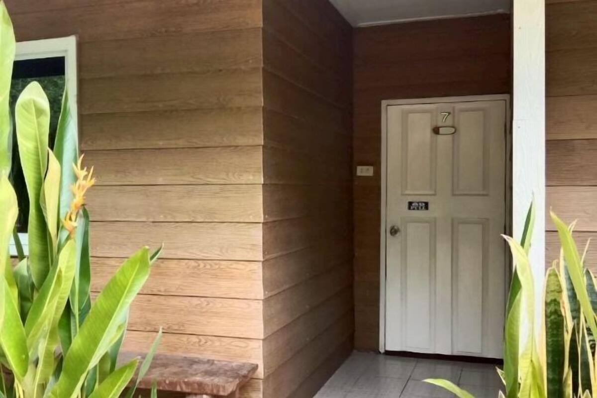 A wooden exterior wall with a door marked '7' and a small bench.